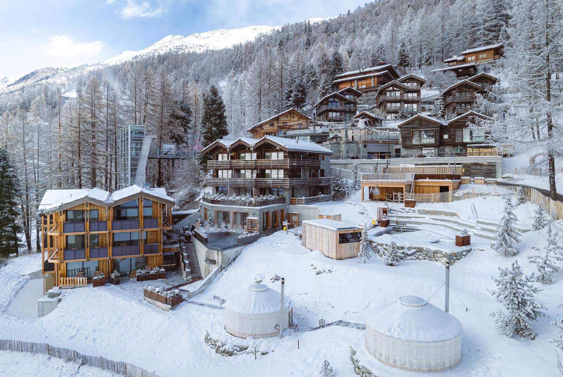 Aussenansicht des Cervo Mountain Resort in Zermatt aus der Ferne im Winter, mit schneebedeckten Dächern.